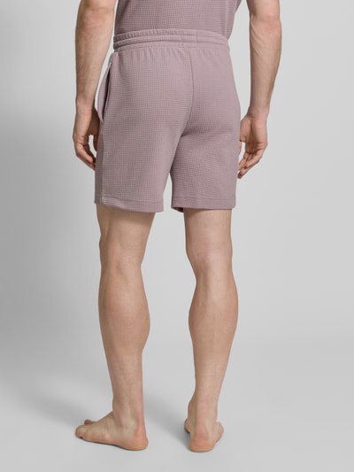 Mężczyzna model nosi Regular Fit Sweatshorts aus Baumwoll-Mix Modell 'AUSTIN' od HUGO w kolorze jednolitym, tekstura waflowa, widok całej sylwetki z tyłu, kontekst: krótkie spodenki męskie z elastycznym pasem, boczne kieszenie, tunel na sznurek, materiał bawełniany mix.