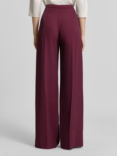Vrouwenmodel draagt Wide Leg Stoffhose met Knopfverschluss van Rinascimento in bordeauxrood Materiaalmix met stretch, bandwijdte 40 cm, binnenbeenlengte 85 cm, wide leg, knoopsluiting, ritssluiting, geheelopname achteraan.