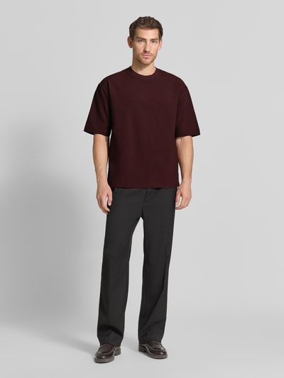 Männermodel trägt T-Shirt mit Strukturmuster und Rundhalsausschnitt von Emporio Armani in Dunkelrot, Modern Fit, Ganzkörperansicht von vorne.