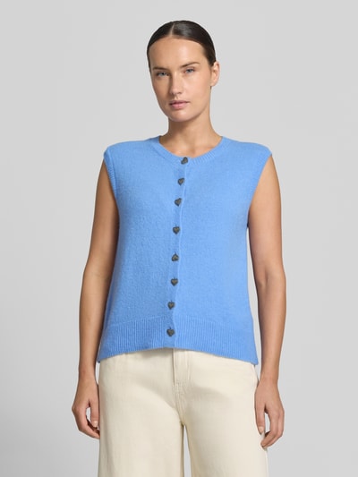 Frauenmodel trägt Strickweste mit Alpaka-Anteil von Milano Italy in Hellblau mit Herz-Knöpfen, feine Struktur, Rundhalsausschnitt, Ganzkörperansicht von vorne.