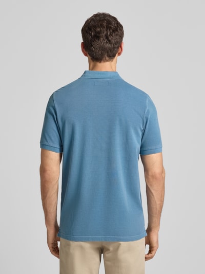 Männermodel trägt Poloshirt aus Baumwolle von MARC O’POLO DENIM in Blau mit Piqué-Struktur, gerader Schnitt, Ganzkörperansicht Rückansicht.