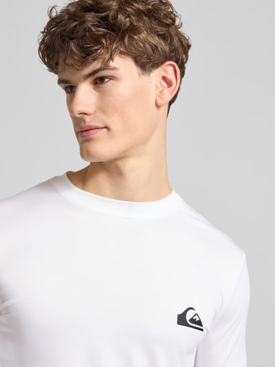 Männermodel trägt Langarmshirt mit Sonnenschutz Modell 'EVERYDAY' von Quiksilver in Weiß, elastischer Stoff, Label-Print, Nahaufnahme Oberkörper.