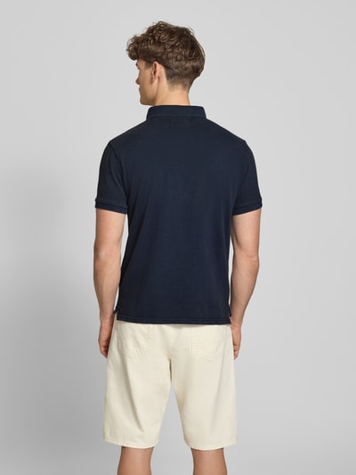 Mężczyzna nosi Regular Fit Poloshirt mit Logo-Stitching von Superdry, granatowy kolor, krótki rękaw, bawełna, długość tyłu w rozmiarze M: 67 cm, krój regular fit, widok całej sylwetki z tyłu.
