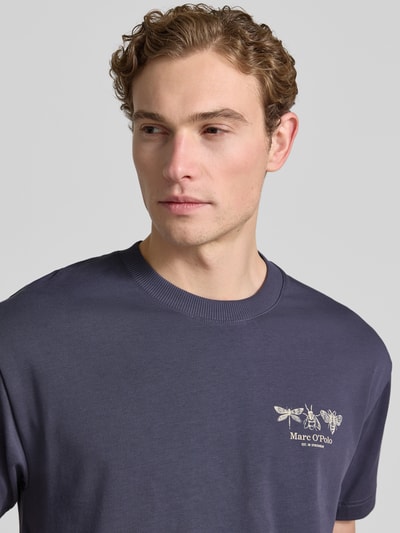 Męskimodel nosi Relaxed Fit T-Shirt aus reiner Baumwolle von Marc O'Polo, jednokolorowy, krój regular fit, nadruk z logo i motywem, okrągły dekolt, krótki rękaw, dżersej, czysta bawełna, zbliżenie na górną część ciała.