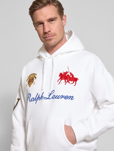 Männermodel trägt Relaxed Fit Hoodie aus katoenmix van Polo Ralph Lauren in effen wit met labelopschrift en kangoeroezak, Nahaufnahme Oberkörper.