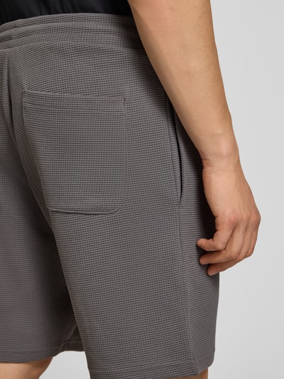 Männermodel trägt Shorts mit Strukturmuster von REVIEW in Grau, Baumwoll-Mix, Regular-Fit, elastischer Bund, Nahaufnahme Rückansicht.