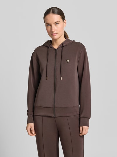 Frauenmodel trägt Sweatjacke mit Kapuze Modell 'OLYMPE' von Guess Activewear, Material-Mix mit Modal-Anteil, Regular-Fit, Label-Applikation, Reißverschluss, einfarbig braun, glatte Textur, Ganzkörperansicht von vorne.