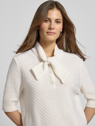 Frauenmodel trägt Strickpullover aus Schurwoll-Kaschmir-Mix mit Schluppe von Marc Cain, Regular-Fit, Stehkragen, Knopfleiste, 1/2-Arm, cremefarben, strukturierte Oberfläche, Rückenlänge 53 cm, Ärmellänge 32 cm, Nahaufnahme Oberkörper.
