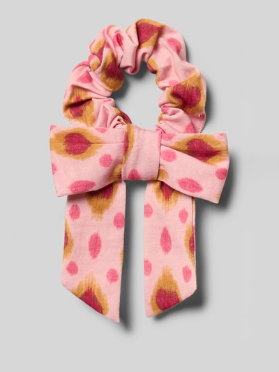 Productfoto, scrunchie van zachte katoen in lichtroze met gevlekte print in roze en oker, grote strik, gladde textuur