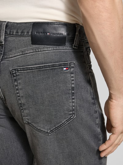 Männermodel trägt Slim Fit Jeans aus Baumwoll-Mix Modell 'BLEECKER' von Tommy Hilfiger in grauer Denim-Optik mit Label-Patch, Detailaufnahme Rückansicht.