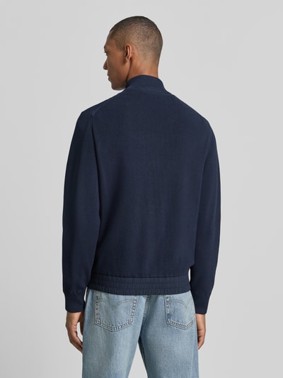 Männermodel trägt Regular Fit Strickjacke aus Baumwoll-Mix Modell 'Kobello' von BOSS, dunkelblau, grob gestrickt, BOSS Orange, Ganzkörperansicht Rückansicht.