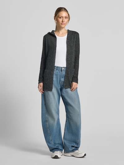 Frauenmodel trägt Regular Fit Cardigan mit Kapuze Modell 'DOFFY' von VERO MODA in Dunkelgrau, kombiniert mit weißem Shirt und Jeans, Ganzkörperansicht von vorne.