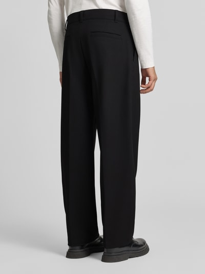 Männermodel trägt High Waist Bundfaltenhose mit Bügelfalten von HUGO, unifarben, Wide Leg, Knopf und verdeckter Reißverschluss, Ganzkörperansicht Rückansicht