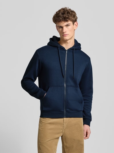 Männermodel draagt Sweatjack met capuchon model 'BRADLEY' van Jack & Jones in donkerblauw, katoenmix, losse pasvorm, ritssluiting, kangoeroezak, ruglengte 74 cm, mouwlengte 63 cm, ganzkörperansicht van voren.