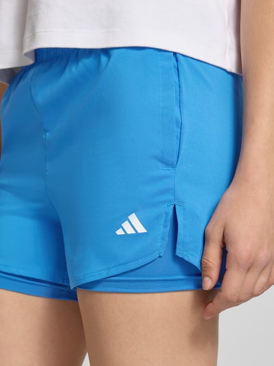 Frauenmodel trägt Regular Fit Sport-Shorts mit elastischem Bund von adidas Sportswear, Optik: Unifarben, Logo-Print, Eingrifftasche, Nahaufnahme Oberschenkel.