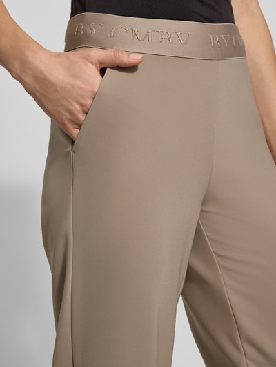 Frauenmodel trägt Stoffhose in verkürzter Passform Modell 'ELENA' von Cambio, Material-Mix, elastischer Logo-Bund, Nahaufnahme Oberkörper.