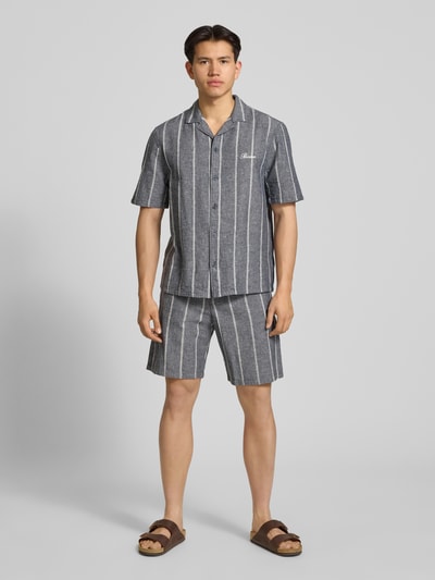 Männermodel trägt Leinenshorts mit Logo-Stitching von REVIEW im Regular Fit, graues Streifenmuster, elastischer Bund, Ganzkörperansicht von vorne.
