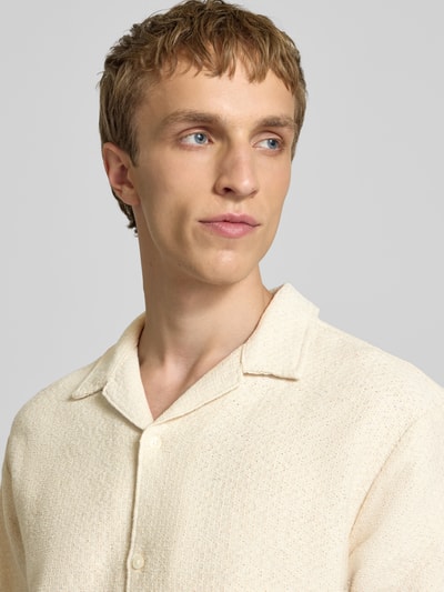 Männermodel trägt Regular Fit Poloshirt mit V-Ausschnitt von Jack & Jones aus reiner Baumwolle, Stricktextur, Nahaufnahme Oberkörper.