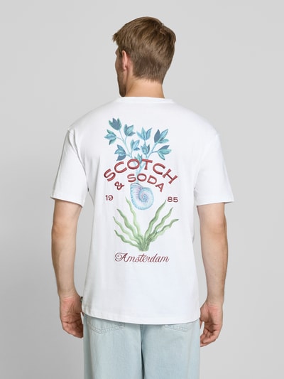 Männermodel trägt Regular Fit T-Shirt aus reiner Baumwolle von Scotch & Soda in Weiß mit Label-Print, Ganzkörperansicht Rückansicht.