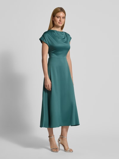 Frauenmodel trägt Relaxed Fit Midikleid mit Stoffband von Christian Berg Cocktail, Satin, gerader Ausschnitt, kurzärmelig, petrol, Ganzkörperansicht von vorne.