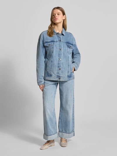 Frauenmodel trägt Jeansjacke mit rückseitigem Label-Patch von Karo Kauer aus Reine Baumwolle im Loose-Fit, Kentkragen, Knopfleiste, Pattentaschen mit Knopfverschluss, seitliche Eingrifftaschen, in hellem Blau mit sichtbarer Struktur; Rückenlänge bei Größe S: 68 cm, Schulterbreite 60 cm, Brustweite 58 cm, Ärmellänge 60 cm; Ganzkörperansicht von vorne.