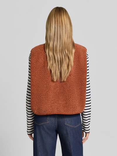 Frauenmodel trägt Relaxed Fit Weste aus Teddyfell Modell 'Hoktown' von American Vintage, orange, weiche Textur, Ganzkörperansicht Rückansicht. Damen Weste mit Logo-Patch, Knopfleiste, Rückenlänge 56 cm, Schulterbreite 43 cm, Brustweite 63 cm.