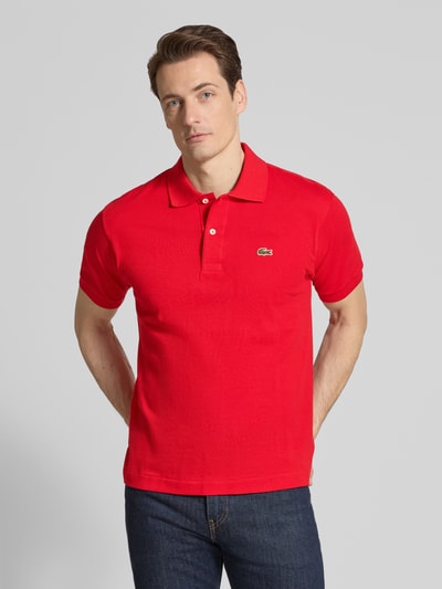 Męski model nosi Regular Fit Poloshirt aus reiner Baumwolle von Lacoste, efekt: jednolity kolor, krój regular fit, wyhaftowane logo, kołnierzyk polo, krótki rękaw, zakończenie rękawów: prążkowane, dół z rozcięciami bocznymi, wykończenie materiału: pika, materiał: bawełna, widok na cały przód.