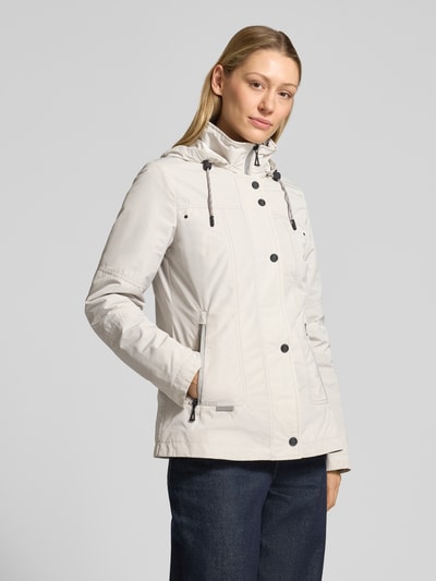Frauenmodel trägt Weather Protection Jack mit Reißverschlusstaschen von Gil Bret in Hellgrau mit Kapuze, Stehkragen und Regular Fit, Ganzkörperansicht von vorne.