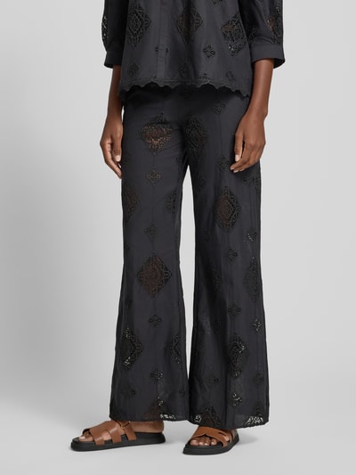 Frauenmodel trägt Hose aus Baumwolle mit Häkelspitze Modell 'MIKE' von Bash, schwarze Flared-Cut Damen Hose, Nahaufnahme Unterkörper von vorne.