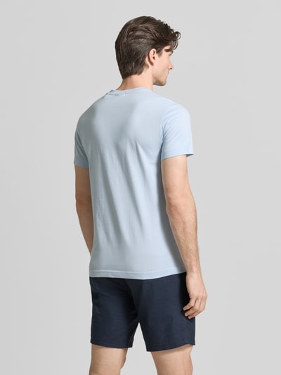Męski model nosi T-Shirt mit Label-Detail od Gant, jasnoniebieska bawełna, prosty krój, długość tyłu 70 cm, widok z tyłu, cała sylwetka.