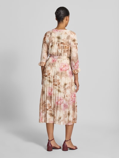 Vrouwenmodel draagt midi-jurk met all-over bloemenprint Model 'Matilda' van ZABAIONE, getailleerde pasvorm, v-hals, 1/2-mouwen, ruglengte maat S 121 cm, borstwijdte 37 cm, mouwlengte 44 cm, volledig in zachte beige- en roze tinten, bloemenmotief, structuur met lichte plooien, rugaanzicht volledige lichaamsopname.