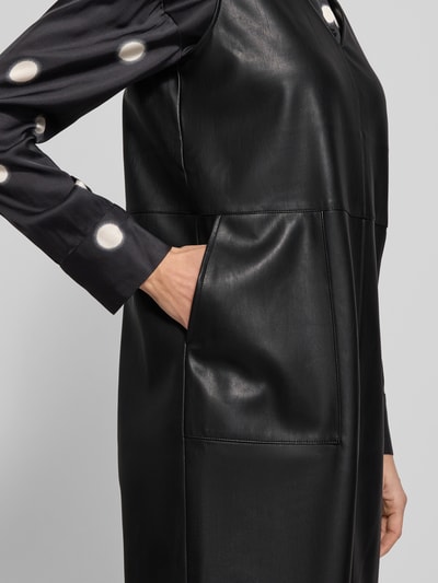 Frauenmodel trägt knielanges Kleid in Leder-Optik Modell 'Wancy' von Opus, mit V-Ausschnitt, Eingrifftaschen, Detailaufnahme Oberkörper.