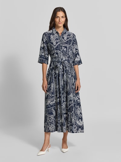 Frauenmodel trägt Hemdblusenkleid aus Viskose-Mix mit Bindegürtel von Christian Berg Woman, blau gemusterte A-Linie, Ganzkörperansicht von vorne.