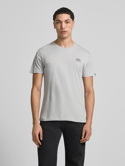 Männermodel trägt Herren T-Shirt mit Label-Details Modell 'BASIC' von Alpha Industries in Hellgrau, Reine Baumwolle, Gerader-Schnitt, Rundhalsausschnitt, Rückenlänge bei Größe M: 67 cm, Ganzkörperansicht von vorne.