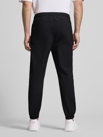 Männermodel trägt Slim Fit Schlupfhose mit Gesäßtasche von CK Calvin Klein, schwarze Farbe, elastischer Bund, Ganzkörperansicht Rückansicht.
