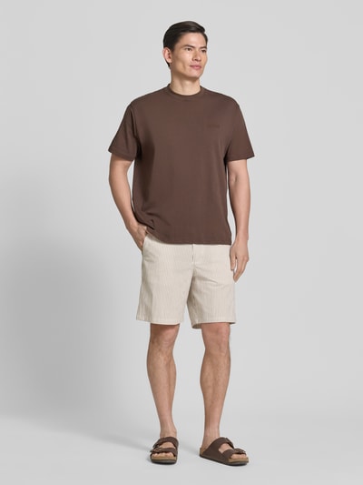 Męski model nosi Regular Fit Bermudas aus Baumwoll-Mix Modell 'KARL' von SELECTED HOMME, wzór w paski, beżowo-brązowy kolor, mieszanka bawełny, seersucker, wpuszczane i tylne kieszenie, szlufki, zapięcie na guzik i zamek, elastyczny pas, Ganzkörperansicht von vorne.