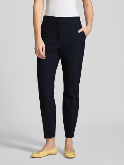 Frauenmodel trägt Regular Fit Schmale Hose mit Bügelfalten von s.Oliver BLACK LABEL, Optik: Unifarben, schwarze Struktur, seitliche Eingrifftaschen, elastischer Bund mit Struktur, angedeutete Gesäßtaschen, Schiebehaken und verdeckter Reißverschluss, Ganzkörperansicht von vorne.