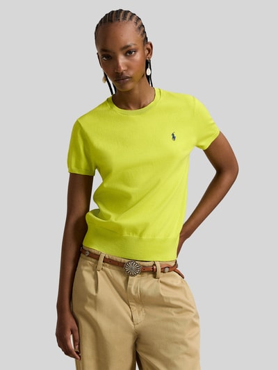 Frauenmodel trägt Regular Fit Kurzarmpullover mit Logo-Stitching von Polo Ralph Lauren, leuchtend gelb, elastischer Baumwoll-Mix, Rundhalsausschnitt, elastische Ärmelabschlüsse, kombiniert mit beiger Hose, Ganzkörperansicht von vorne.