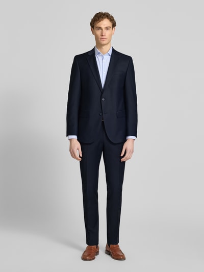 Męski model nosi Slim Fit Anzug mit 2-Knopf-Sakko Modell 'Grant' von Pierre Cardin, granatowy, gładka faktura, krój slim fit, garnitur z domieszką wełny, marynarka z klapami i kieszeniami z patkami, spodnie z kantem, Szerokość w rozmiarze 50: 43 cm, długość z tyłu: 76 cm, szerokość ramion: 41 cm, długość rękawa: 65 cm, długość nogawki wewnętrznej: 83 cm, pełen widok z przodu.