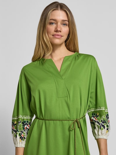Frauenmodel trägt Knielanges Kleid mit Bindegürtel von Marc Cain aus Reine Baumwolle, Gerader-Schnitt, V-Ausschnitt, Nahaufnahme Oberkörper.