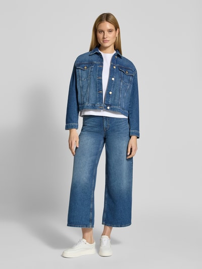Modelka nosi T-Shirt mit Blumenstickerei von Christian Berg Woman z czystej bawełny, prosty krój, okrągły dekolt, haft kwiatowy, rękaw 1/2, długość tyłu w rozm. S: 54 cm, jasnoniebieska dżinsowa kurtka i spodnie, białe buty sportowe, widok całej sylwetki z przodu.
