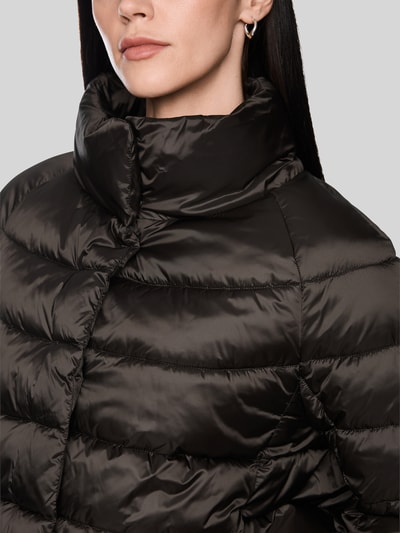 Frauenmodel trägt Steppjacke mit Stehkragen und Label-Detail von Marc Cain in Schwarz, glänzende Oberfläche, Nahaufnahme Oberkörper. Damen Steppjacke, Regular Fit, Eingrifftaschen, Rückenlänge 56 cm, Schulterbreite 41 cm, Brustweite 55 cm, Ärmellänge 73 cm.