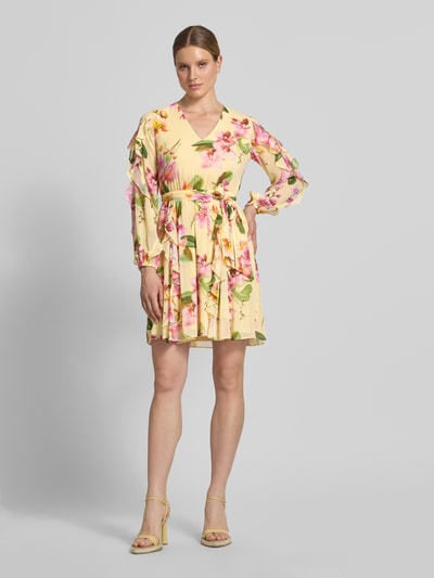 Frauenmodel trägt Knielanges Cocktailkleid mit Chiffons und Bindegürtel von V by Vera Mont, creme, floraler Allover-Look, Taillierter Schnitt, V-Ausschnitt, Volants, Rückenlänge 94 cm, Brustweite 48 cm, Ärmellänge 63 cm, Ganzkörperansicht von vorne.