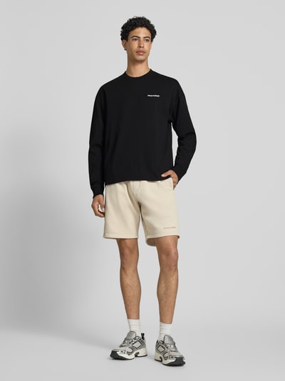 Männermodel trägt Oversized Sweatshirt mit Logo-Stitching Modell 'Rusk' von Pegador aus Reine Baumwolle, schwarze Farbe, Ganzkörperansicht von vorne. Herren Sweatshirt, Oversized-Fit, Rückenlänge bei Größe M: 61 cm.