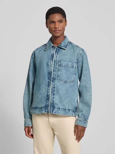 Męskki model nosi kurtkę jeansową Regular Fit Jeansjacke aus reiner Baumwolle model 'LUNEY BO' von BOSS Orange w niebieskim kolorze, widok całej sylwetki od przodu.