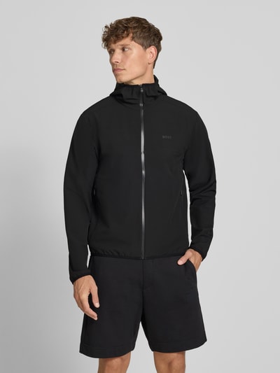 Mężczyzna model nosi czarną kurtkę treningową Regular Fit Trainingsjacke mit Kapuze Modell 'LW_COMMUTERPRO' od BOSS Green, gładka faktura, całkowity widok z przodu