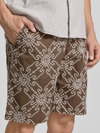 Männermodel trägt Shorts aus Leinen-Mix mit elastischem Bund und Kordelzug von MCNEAL, Relaxed-Fit, braun gemustert, Nahaufnahme Oberschenkel.
