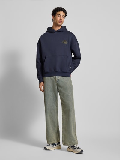 Männermodel trägt Oversized Hoodie mit Label-Stitching von PROHIBITED, dunkelblau, Baumwoll-Mix, Känguru-Tasche, Ganzkörperansicht von vorne.