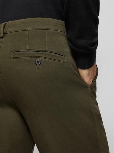 Männermodel trägt olivgrüne Straight Fit Chino aus Baumwoll-Mix Modell 'Miles' von Selected, strukturierte Oberfläche, Nahaufnahme Rückansicht, Herren Chino von Selected.