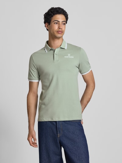 Männermodel trägt Slim Fit Poloshirt mit Logo-Stitching Modell 'Reed' von SERGIO TACCHINI aus elastischem Baumwoll-Mix in Grün, Kurzärmelig, Polokragen, Rückenlänge bei Größe M 71 cm, Ganzkörperansicht von vorne.